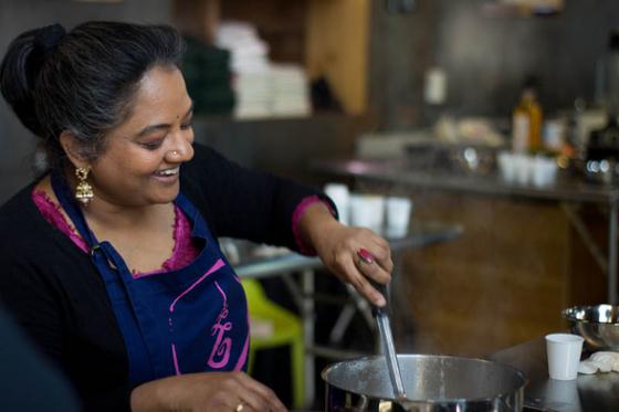 Photo of a South Asian woman leading a cooking demonstration on Eden Hall Campus